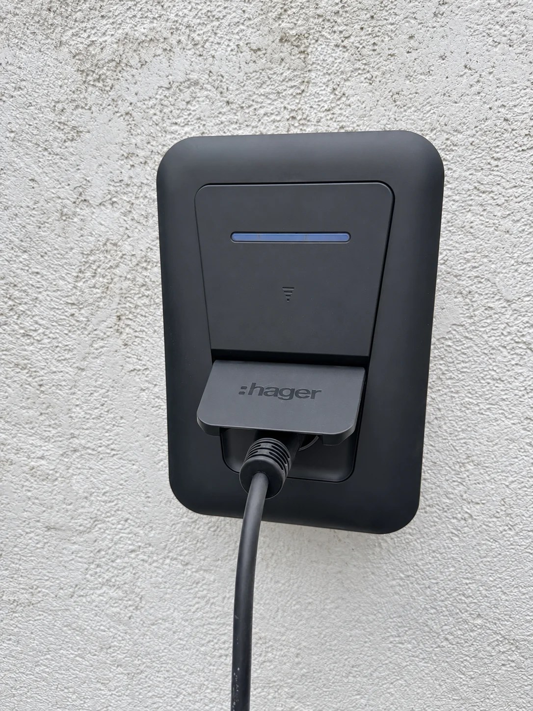 Borne de recharge Hager installée sur une façade grise